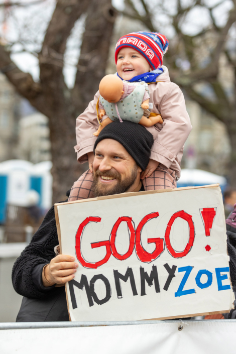 Ein Mann hält ein Schild mit der Aufschrift „Gogo Mommy Zoe“.