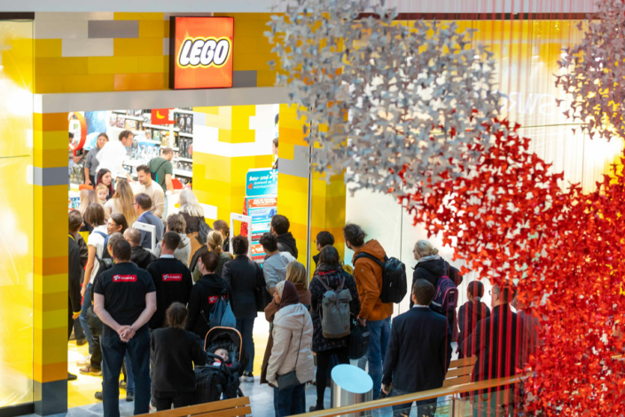 A group of people are standing in front of a Lego store.
