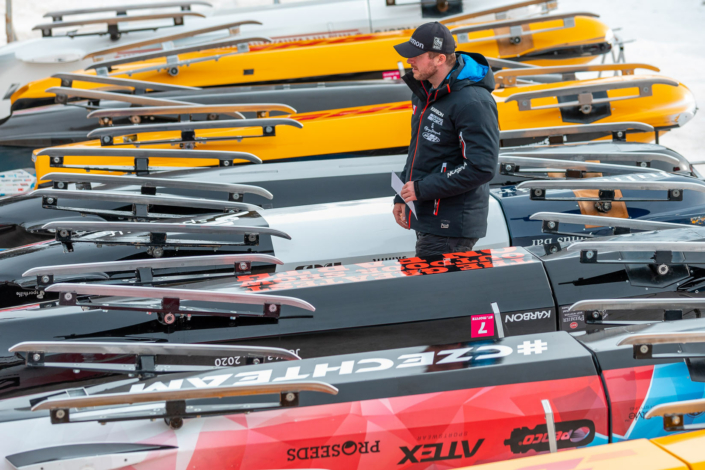 A man stands next to a row of ski boats.