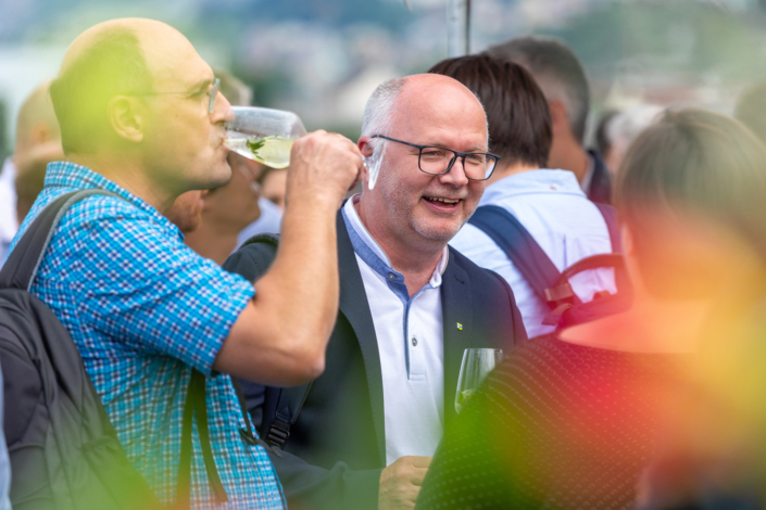 Eine Gruppe von Menschen trinkt Wein bei einer Veranstaltung im Freien.