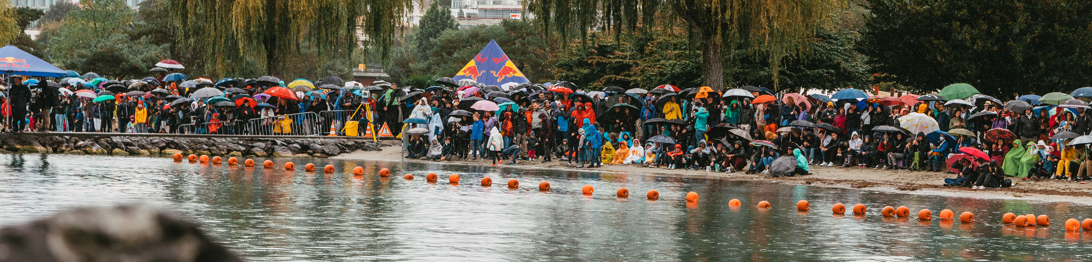 Eine Menschenmenge steht in der Nähe eines Gewässers.